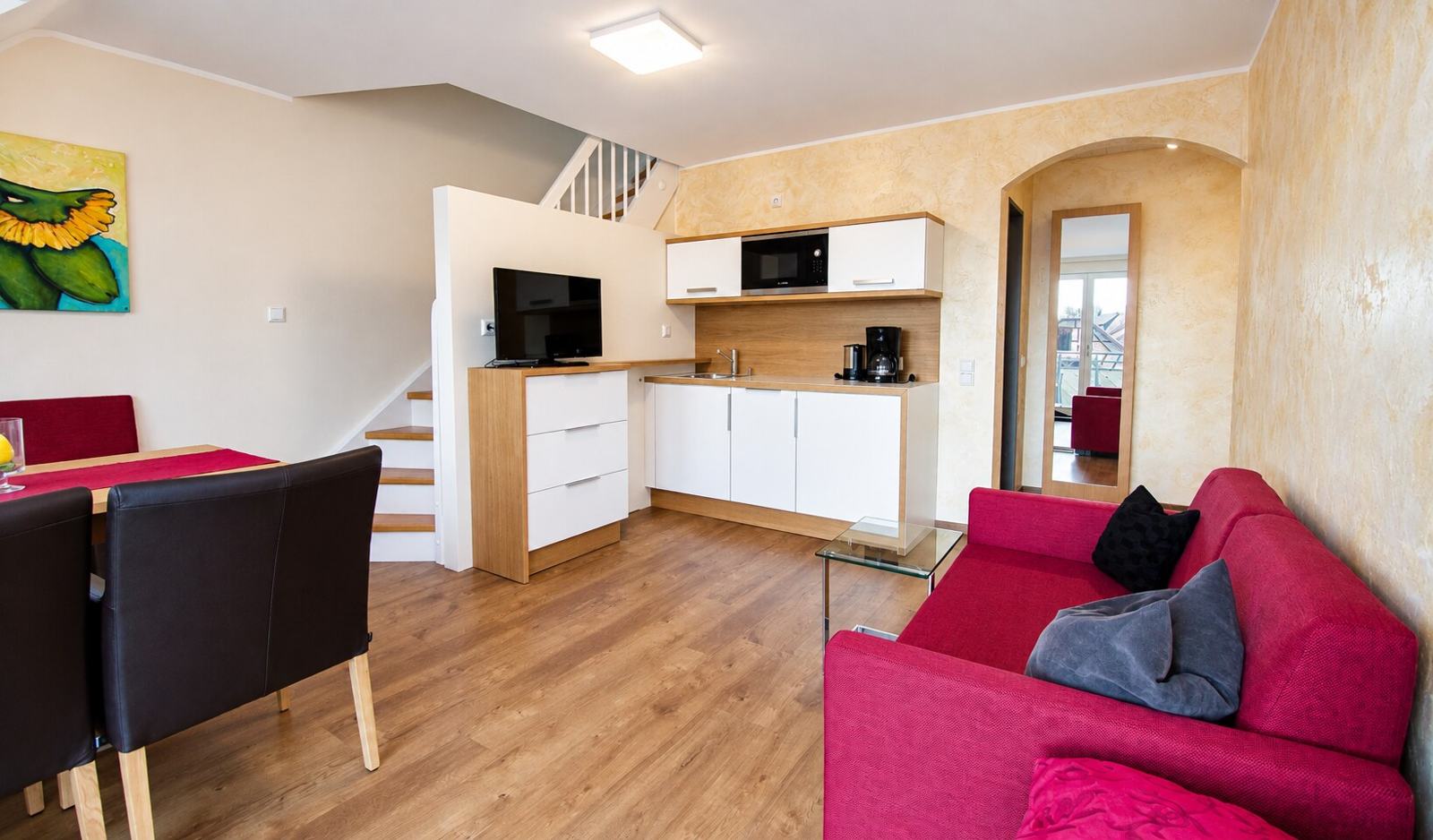 Salón luminoso con cocina pequeña y escalera a la zona de dormitorio en el apartamento en dos niveles
