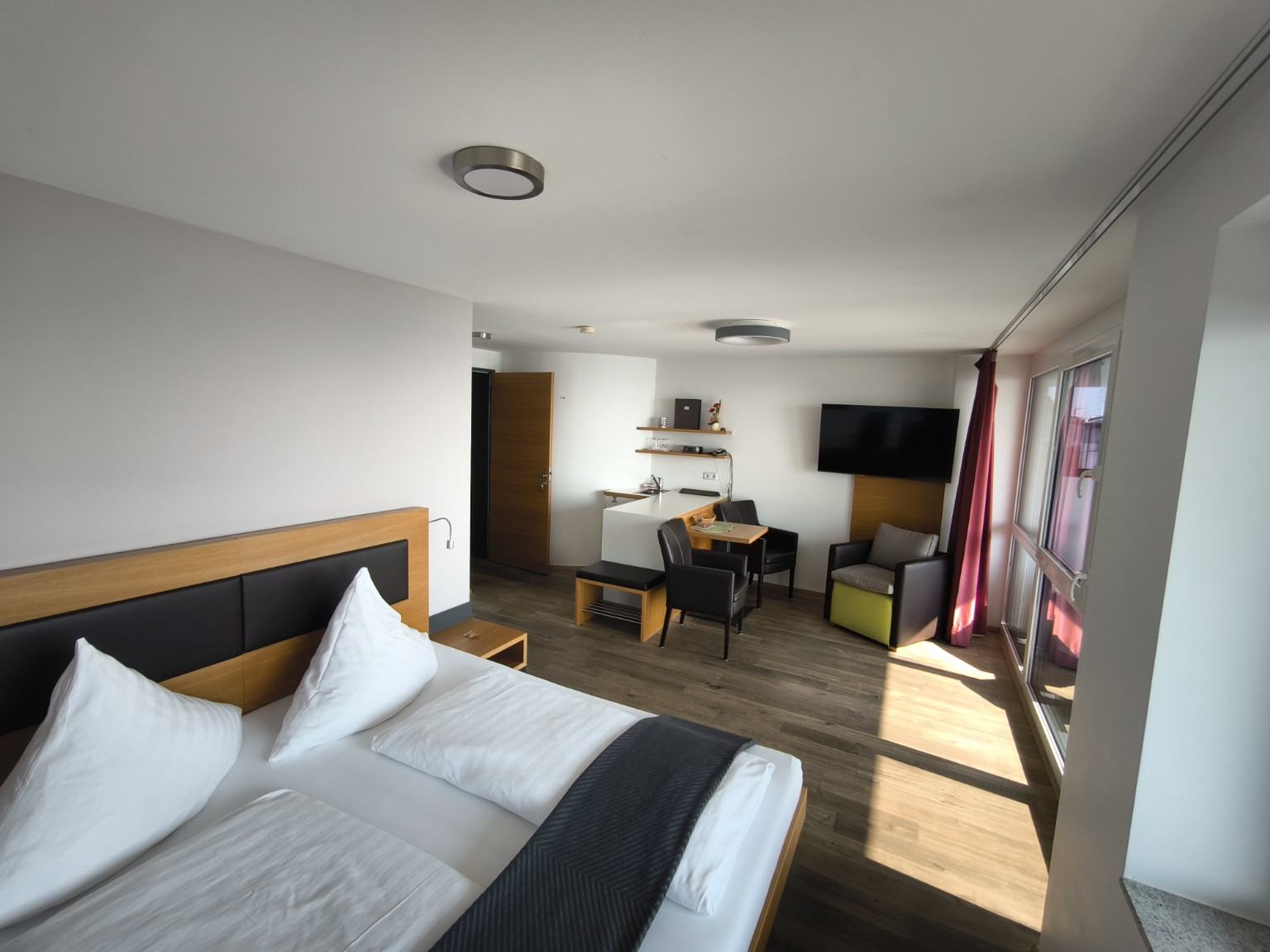 Amplia habitación doble Deluxe con cama doble, zona de estar y grandes ventanales al lago de Constanza