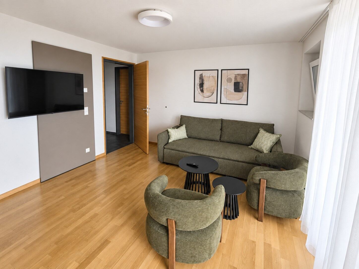 Luminosa zona de sofá verde con dos sillones en el apartamento Superior de tres habitaciones